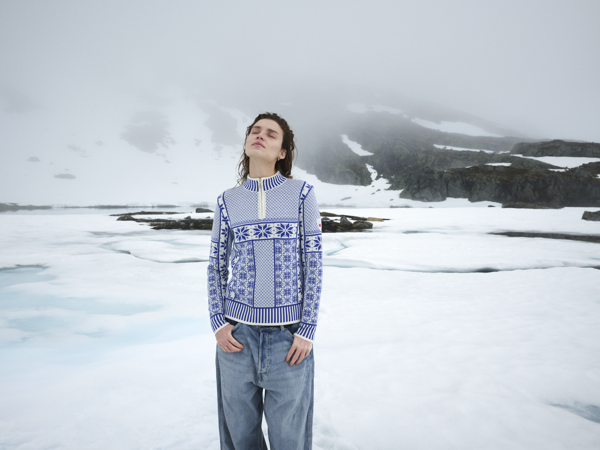 Female model standing in the snow wearing a wool sweater
